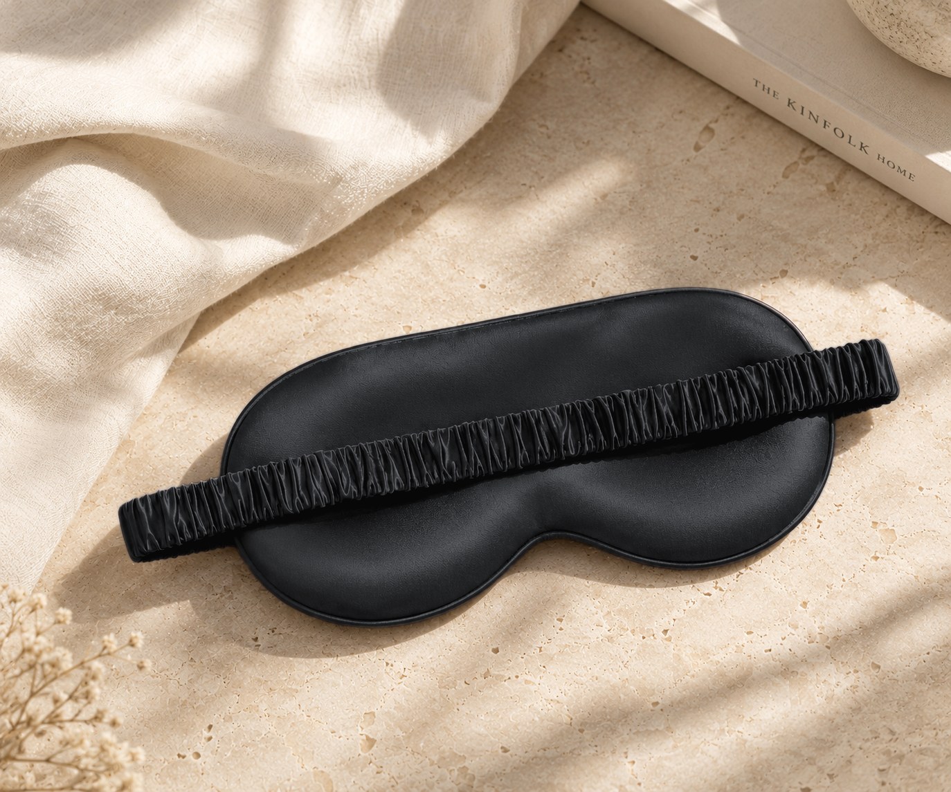 Black mulberry silk sleep eye mask on a sunlit stone surface