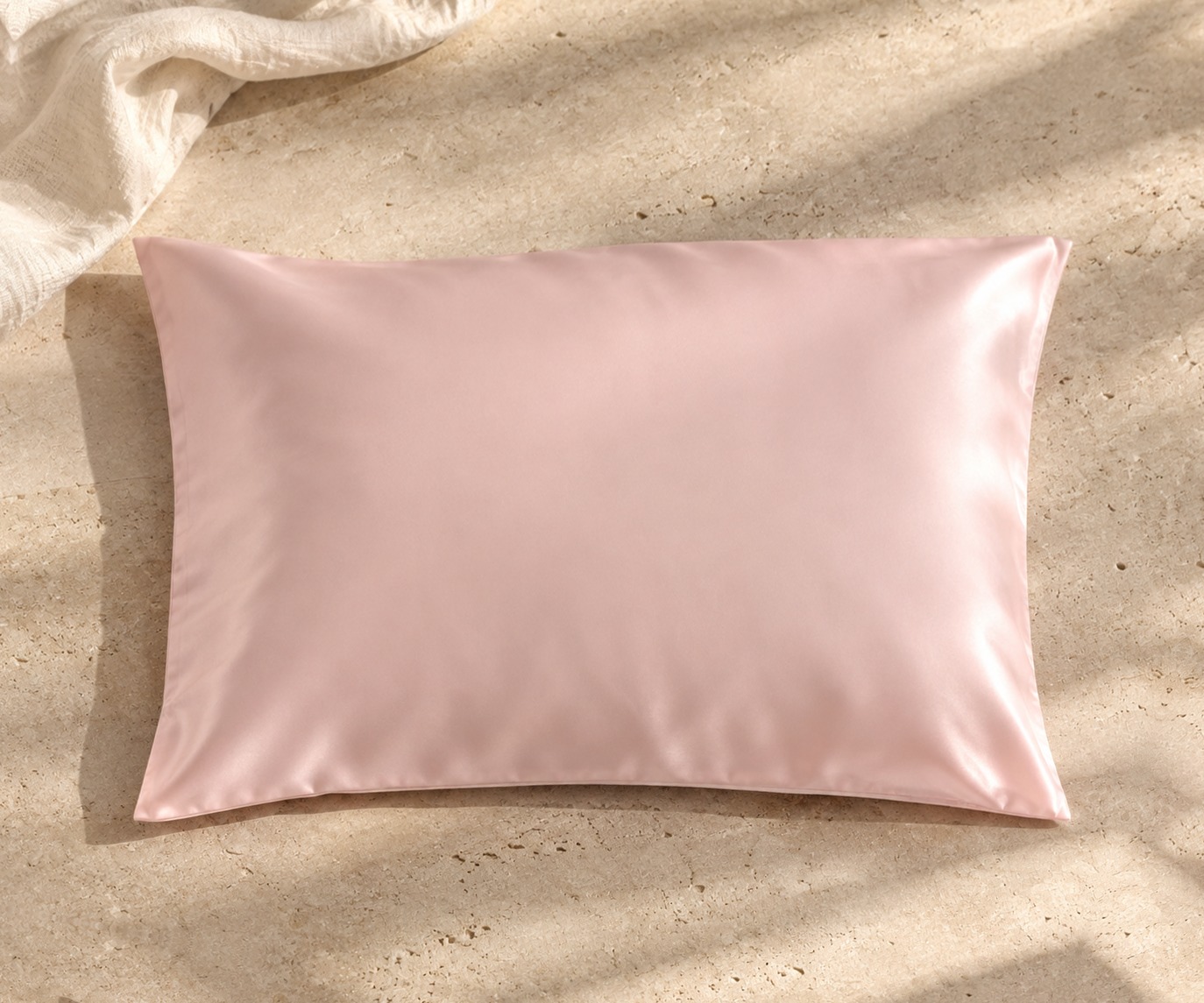 Blush pink mulberry silk pillowcase on sunlit stone